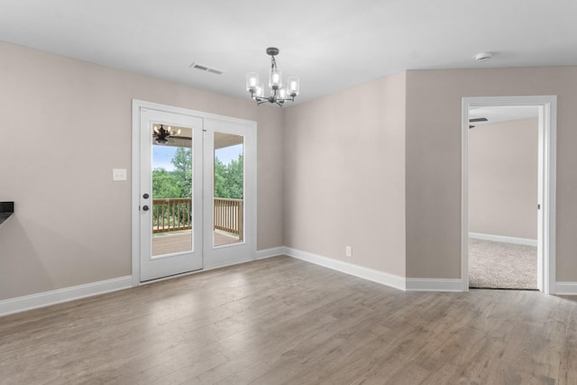 spare room featuring baseboards, visible vents, an inviting chandelier, and wood finished floors