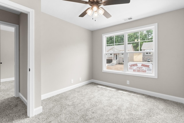 carpeted empty room featuring a ceiling fan, visible vents, and baseboards