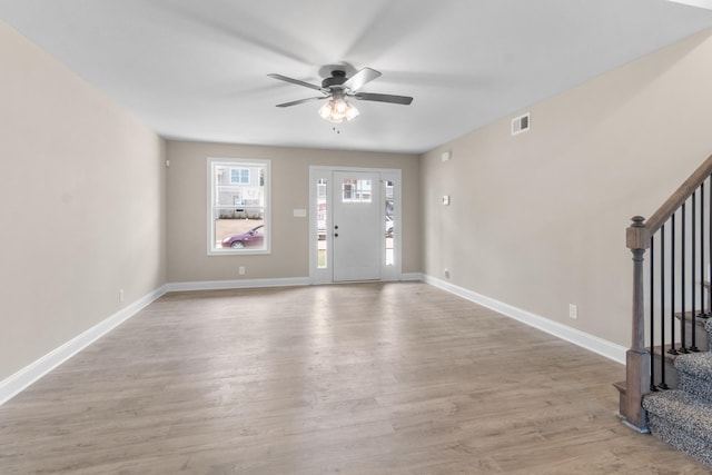 entryway with visible vents, light wood-style floors, a ceiling fan, baseboards, and stairs