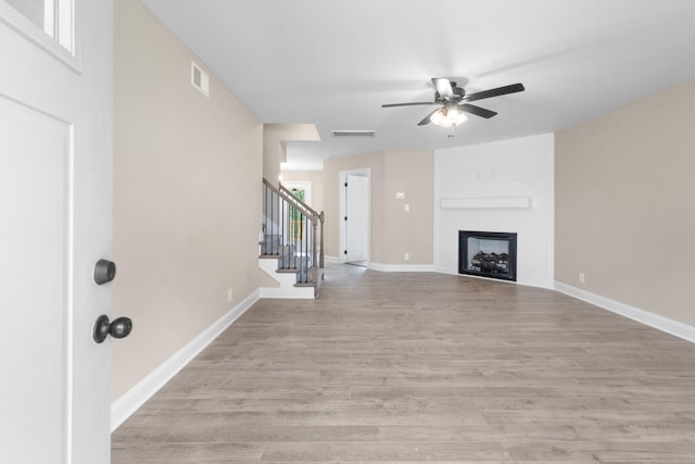 unfurnished living room with ceiling fan, light wood-type flooring, and a fireplace