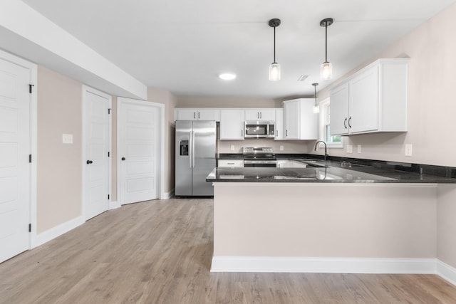 kitchen with stainless steel appliances, light wood finished floors, a peninsula, and decorative light fixtures