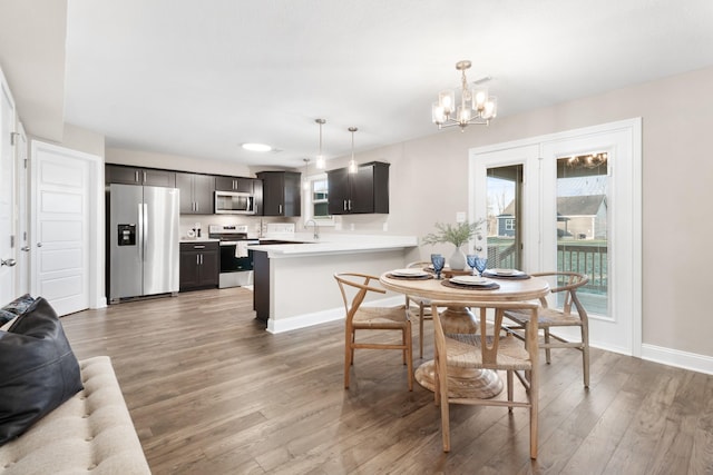 dining space with sink, hardwood / wood-style floors, and a notable chandelier