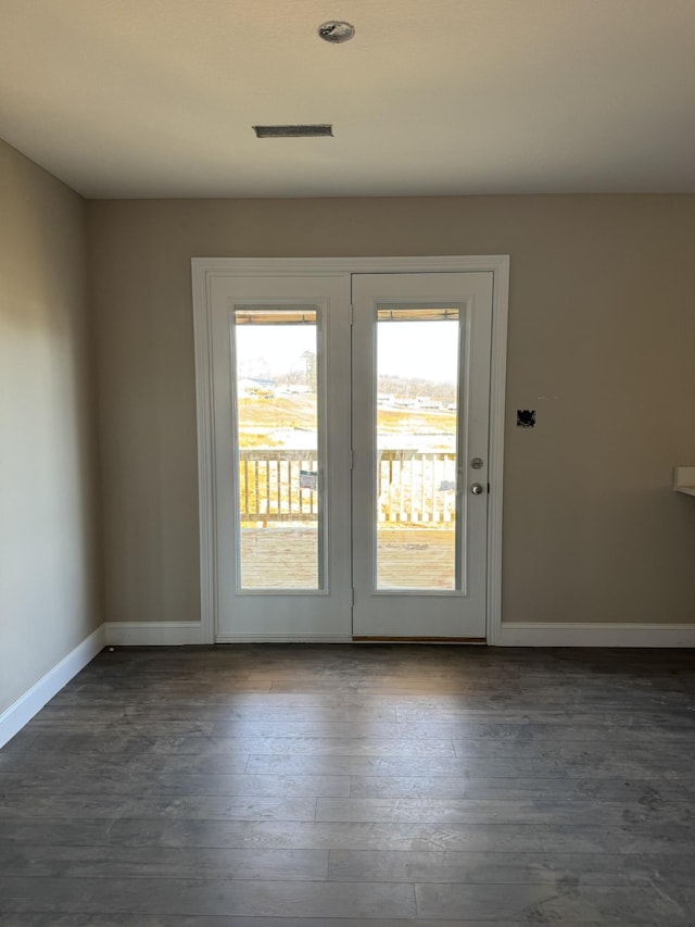 unfurnished room featuring dark wood-type flooring, visible vents, and baseboards