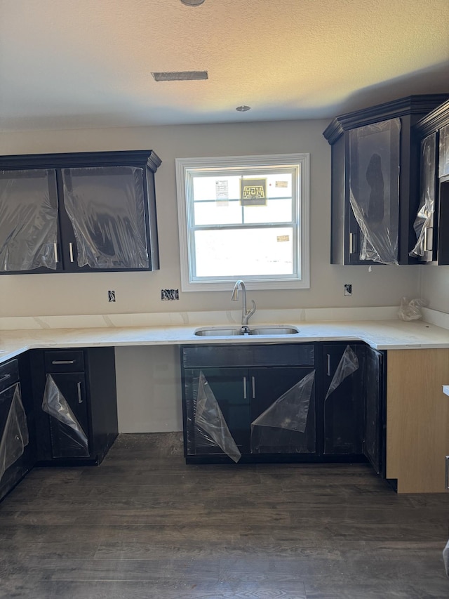 kitchen with a textured ceiling, light countertops, a sink, and dark wood finished floors