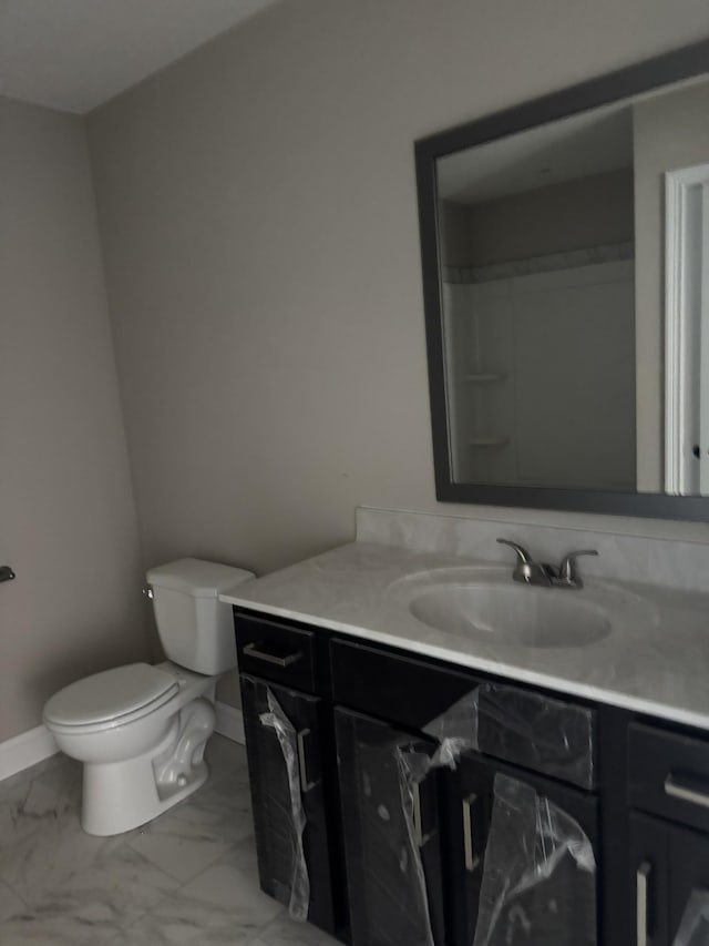 bathroom with toilet, marble finish floor, baseboards, and vanity