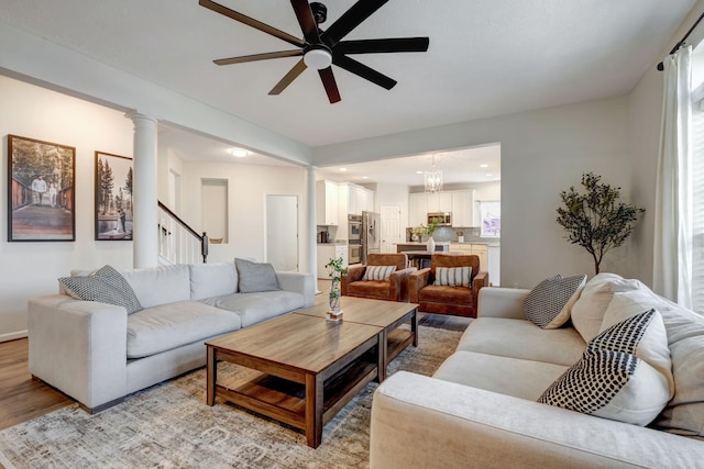 living room with ceiling fan with notable chandelier, decorative columns, a wealth of natural light, and light hardwood / wood-style flooring