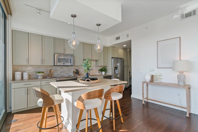 kitchen with dark hardwood / wood-style flooring, tasteful backsplash, stainless steel appliances, pendant lighting, and a breakfast bar area