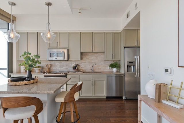 kitchen featuring pendant lighting, sink, light stone countertops, dark hardwood / wood-style flooring, and stainless steel appliances