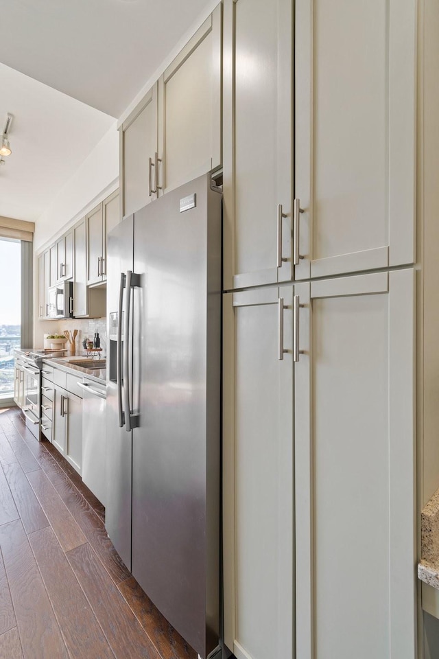 kitchen featuring light stone countertops, stainless steel appliances, dark wood-type flooring, and sink