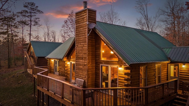 back house at dusk featuring a wooden deck