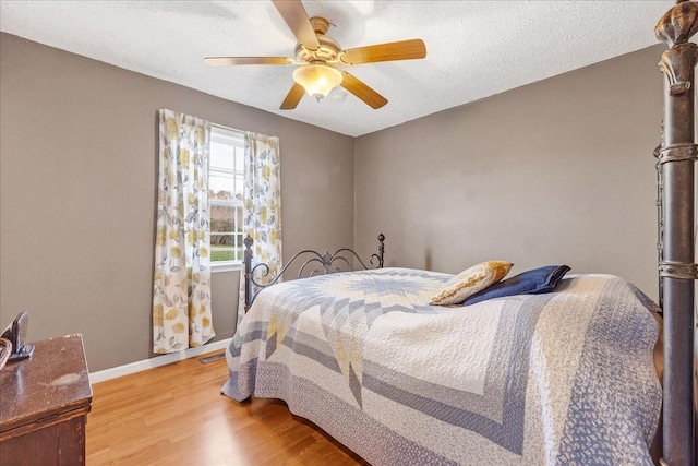 bedroom with ceiling fan, light hardwood / wood-style floors, and a textured ceiling