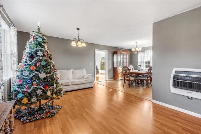 living room featuring heating unit, light hardwood / wood-style floors, and a notable chandelier