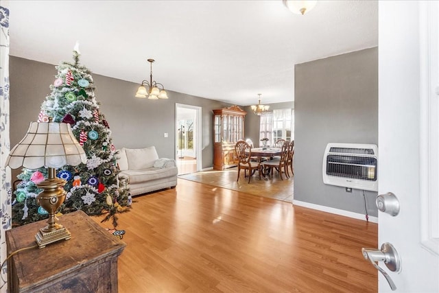 living room with heating unit, hardwood / wood-style flooring, and a notable chandelier