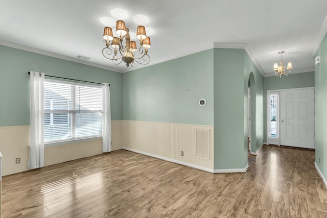 spare room with crown molding, hardwood / wood-style floors, and a chandelier