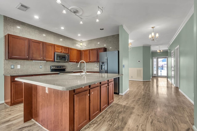 kitchen featuring light wood-type flooring, stainless steel appliances, crown molding, a center island with sink, and a chandelier