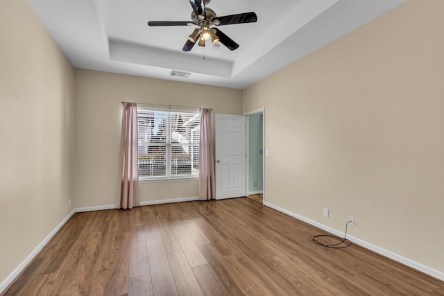 spare room featuring hardwood / wood-style floors, ceiling fan, and a tray ceiling