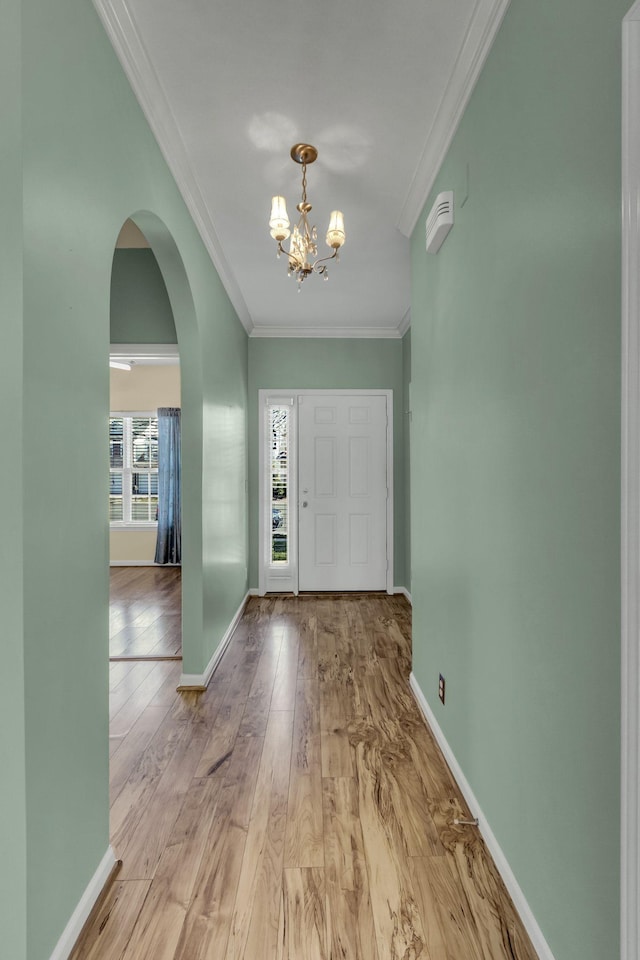 entryway with a chandelier, crown molding, and light hardwood / wood-style flooring