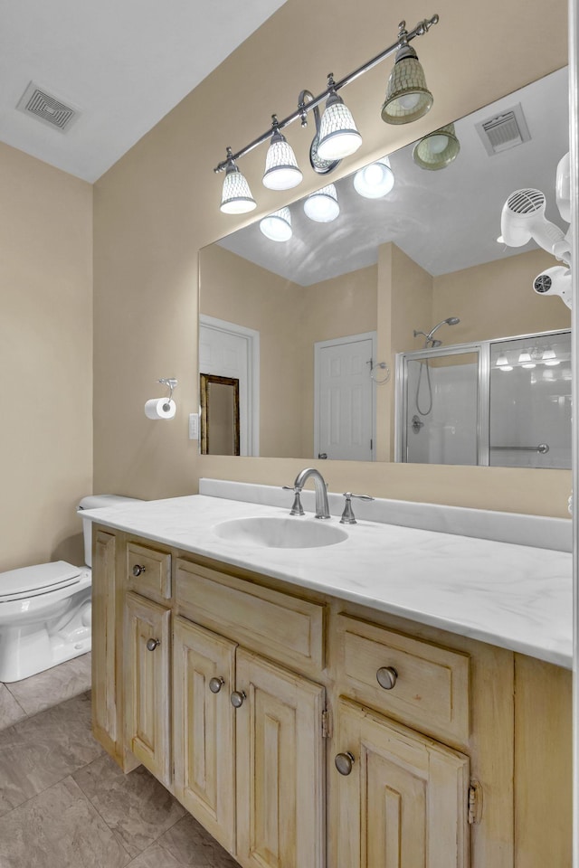 bathroom with tile patterned floors, vanity, toilet, and an enclosed shower