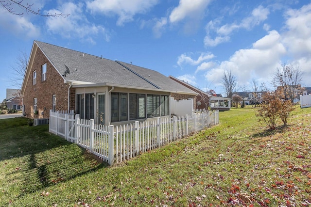 back of house with a lawn, a sunroom, and central AC unit