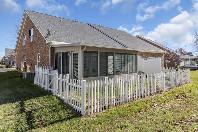 rear view of property with central AC unit, a sunroom, and a yard