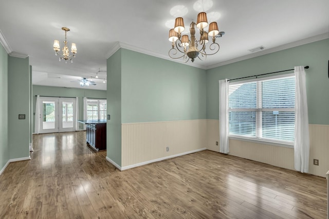 unfurnished room with wood-type flooring, ceiling fan with notable chandelier, and ornamental molding