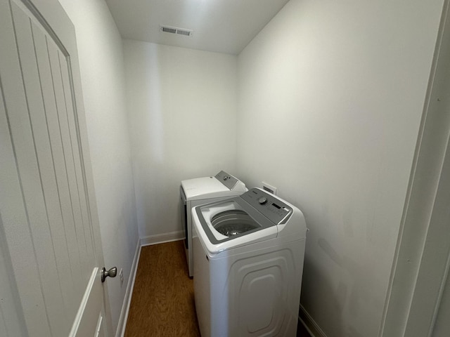 clothes washing area with dark wood-type flooring and washing machine and clothes dryer