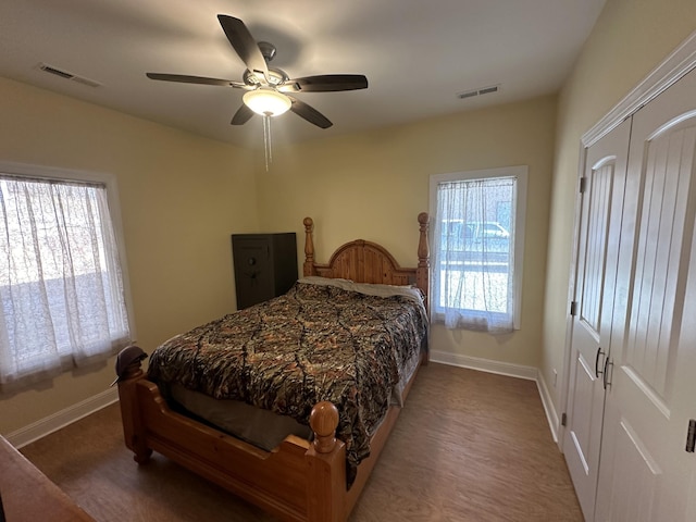 bedroom with hardwood / wood-style floors, ceiling fan, and multiple windows