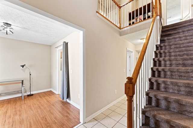 stairway with wood-type flooring and a textured ceiling