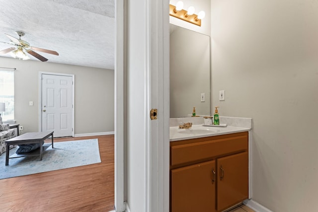 bathroom featuring ceiling fan, hardwood / wood-style floors, vanity, and a textured ceiling