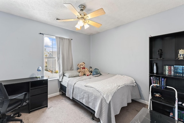 carpeted bedroom featuring ceiling fan and a textured ceiling