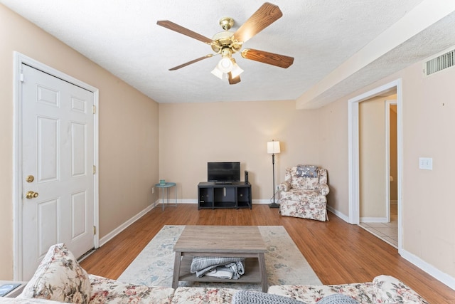 living room with ceiling fan, a textured ceiling, and hardwood / wood-style flooring