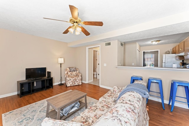 living room with hardwood / wood-style floors, a textured ceiling, and ceiling fan