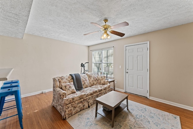 living room with ceiling fan, a textured ceiling, and hardwood / wood-style flooring