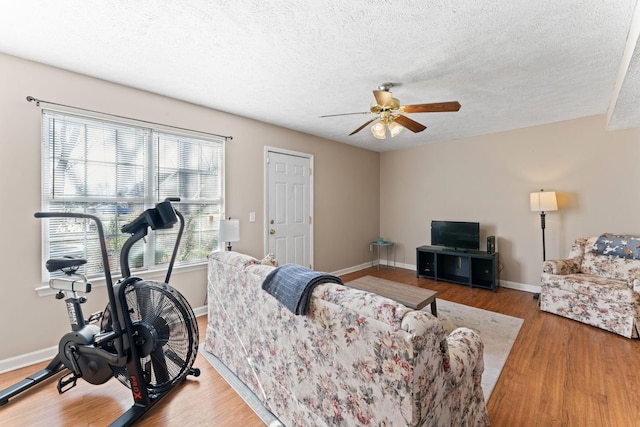 living room featuring wood-type flooring, a textured ceiling, and ceiling fan