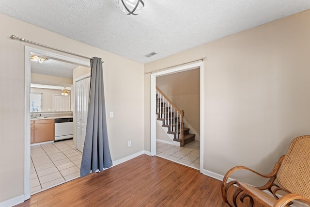 interior space featuring a textured ceiling, light wood-type flooring, ceiling fan, and sink