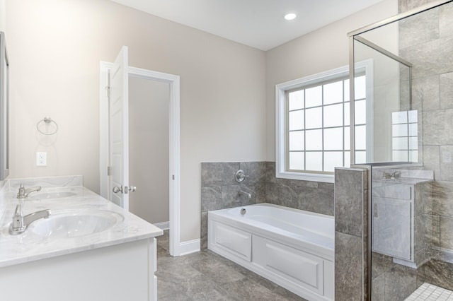 full bathroom with double vanity, a bath, a stall shower, and a sink