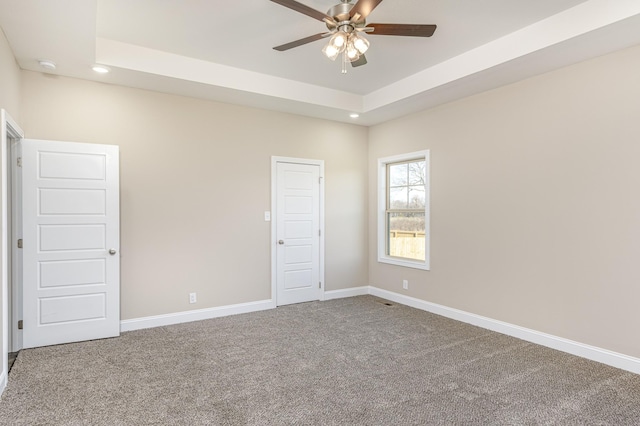 unfurnished bedroom featuring recessed lighting, baseboards, a raised ceiling, and carpet floors