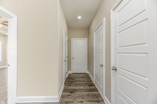 corridor with dark wood finished floors, recessed lighting, and baseboards