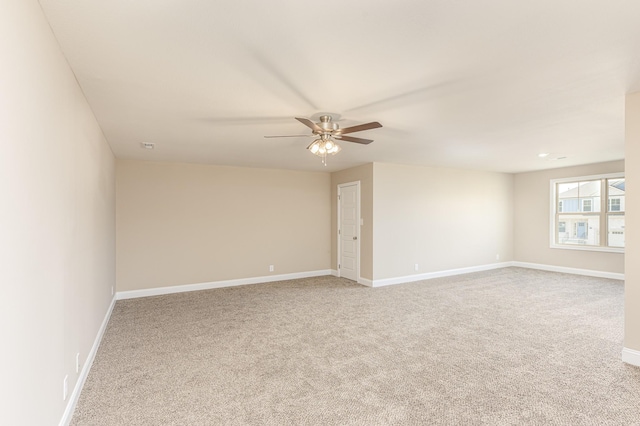 carpeted empty room featuring baseboards and a ceiling fan