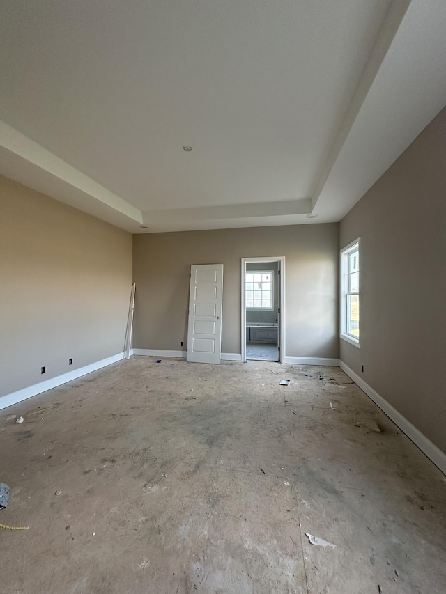 empty room featuring a tray ceiling and baseboards