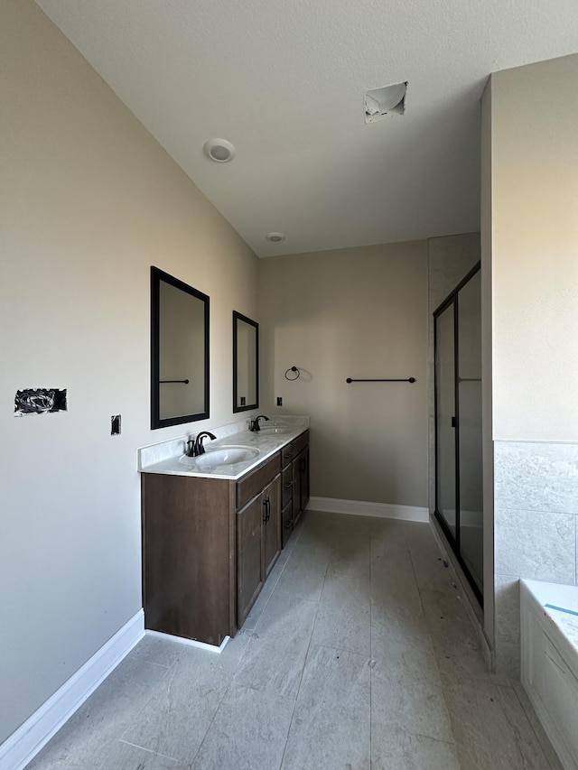 bathroom with a garden tub, double vanity, a stall shower, and a sink