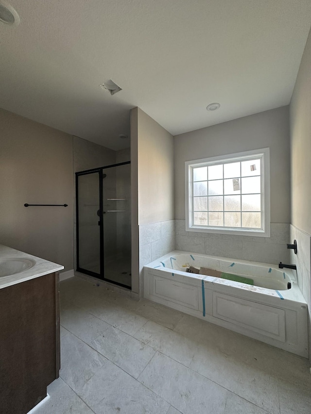 bathroom with vanity, a garden tub, and a shower stall