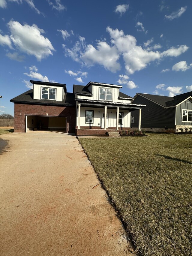 view of front of home with brick siding, a front lawn, concrete driveway, covered porch, and an attached garage