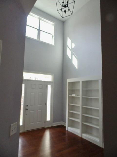 entrance foyer featuring a towering ceiling, dark hardwood / wood-style floors, and a notable chandelier