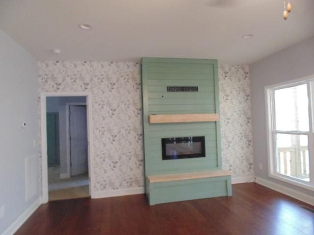 unfurnished living room with a large fireplace and dark wood-type flooring