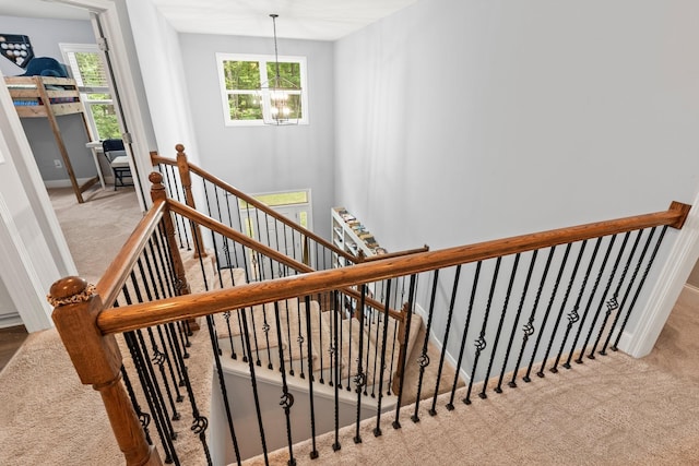 stairs with a notable chandelier and carpet floors