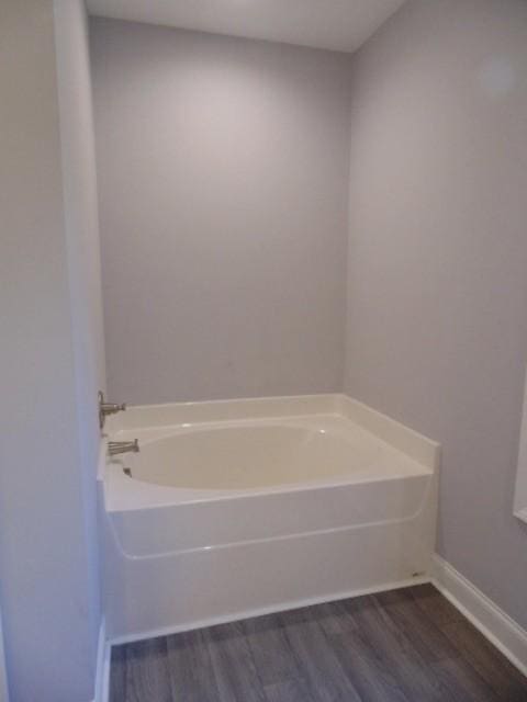 bathroom with a washtub and wood-type flooring