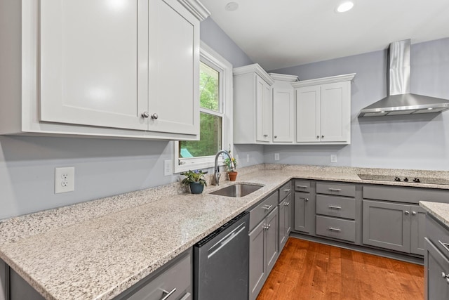 kitchen featuring sink, stainless steel dishwasher, wall chimney exhaust hood, gray cabinets, and hardwood / wood-style flooring