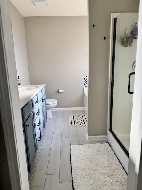 full bathroom with independent shower and bath, vanity, wood-type flooring, and toilet