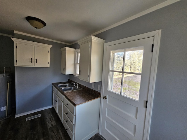 kitchen featuring ornamental molding, gas water heater, sink, white cabinets, and dark hardwood / wood-style floors